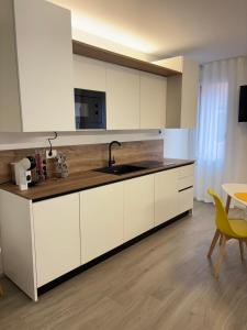 a kitchen with white cabinets and a sink and a table at Golden House by ApartSuite in Chioggia
