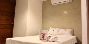 a room with a bed with white sheets and towels at Hostal Pulpos in Bombiso