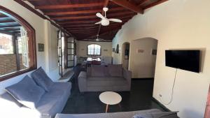 ein Wohnzimmer mit einer Couch und einem Deckenventilator in der Unterkunft Casa com 6 Suites, piscina e estacionamento in Ilhabela