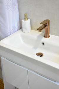 a white bathroom sink with a gold faucet at Studio Bire in Lumbarda +17 photos