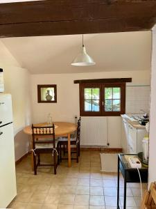a kitchen with a table and a table and a refrigerator at La petite maison in Saint-Mars-dʼOutillé