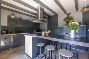 une cuisine avec des placards bleus et un grand îlot avec des tabourets dans l'établissement Domaine Chez Feldus, à Villers-Farlay