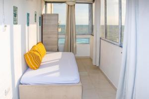 a bed with a yellow pillow in a room with windows at Ocean view - 77Rentals in Cartagena de Indias