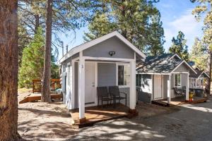 a small white cabin with a porch in the woods at Baby Bear - A delightful studio style property in the perfect central location! in Big Bear Lake