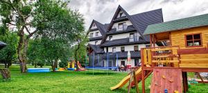 uma casa com um parque infantil em frente a um edifício em DOM WYPOCZYNKOWY ŻAK em Białka Tatrzanska