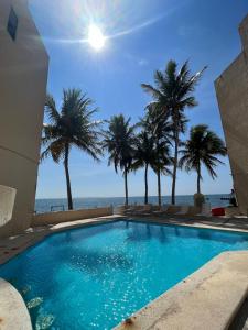 a swimming pool with palm trees and the ocean at Hermoso departamento frente al mar vista increíble in Cancún