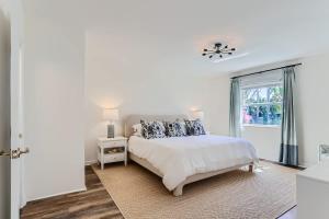 a white bedroom with a bed and a window at The Glenn House - Gather Poolside in a Breezy South End Getaway in West Palm Beach
