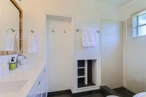 a white bathroom with a shower and a sink at The Glenn House - Gather Poolside in a Breezy South End Getaway in West Palm Beach