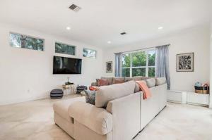 a living room with a couch and a tv at Gregory Place - Dine Alfresco by the Pool in South End Sophistication in West Palm Beach