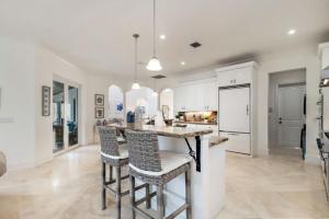 a kitchen with white cabinets and bar stools at Gregory Place - Dine Alfresco by the Pool in South End Sophistication in West Palm Beach +27 photos