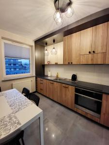 a kitchen with wooden cabinets and a table and a window at Nowowarszawska 130 Apartamenty LUNA Bialystok in Białystok