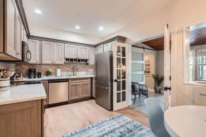 een keuken met een roestvrijstalen koelkast en een tafel bij Northwood Haven - Light-Filled Bungalow Close to Rybovich Marina in West Palm Beach