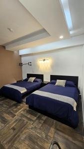 two beds in a room with blue sheets at A29 SUITE BLACK MAX para 1 a 4 personas Modernas Suites en Casona Acequia - Confort y Estilo en Cuautitlán Izcalli" in Cuautitlán Izcalli