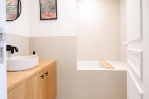 a bathroom with a white sink and a wooden counter at We Parisian Vanneau Cozy Home in Paris +23 photos