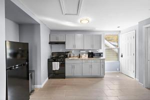 Una cocina con gabinetes blancos y una estufa negra. en Peaceful Hideaway - NYC & NWK with free parking, en Newark