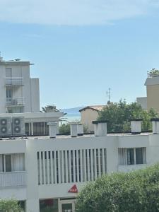 a white building with trees in front of it at Riviera Retreat - Steps to Beach & Shops, Balcony & AC in Saint-Laurent-du-Var