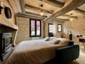 a bedroom with a large bed and a fireplace at Le Cottage des Chalands - classé 3 étoiles in Saint-Georges-sur-Cher
