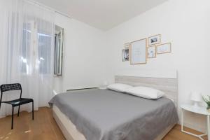 a white bedroom with a bed and a chair at Apartment Ljerka in Postira +31 photos