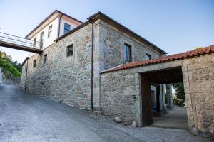 an old stone building with a garage and a bridge at Quinta da Mata in Ponte da Barca