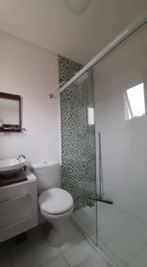 a bathroom with a toilet and a glass shower at Casa aconchegante na praia na praia da Enseada in Guarujá