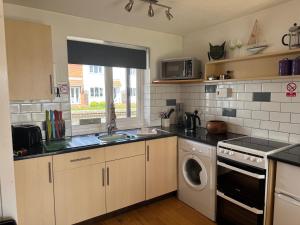 a kitchen with a washer and a sink and a dishwasher at Blackfriars in Wroxham