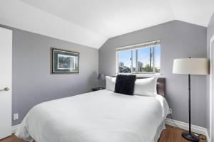 Un dormitorio con una gran cama blanca con ventana. en Family-Friendly 3BR Home, en Vancouver