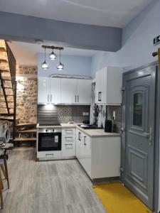 a kitchen with white cabinets and a door at Amyrissa House in Mesochórion
