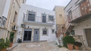 a white house with a balcony on a street at Amyrissa House in Mesochórion