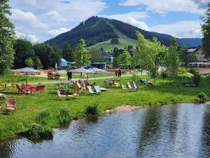 a group of chairs and tables next to a river at Schwarzwald-Ferienwohnungen Begert in Baiersbronn