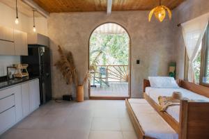 a bedroom with a bed and a kitchen with a window at Salvia Madre Hotel Boutique in Guachaca