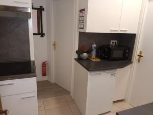 a kitchen with white cabinets and a microwave at Appartement entier au RDC - Ideal pour travailleurs ou voyageurs en famille jusqu à 6p in Mulhouse