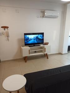 Una sala de estar con un televisor de pantalla plana sobre un soporte. en Apartamento a Pasos del Centro, en Posadas