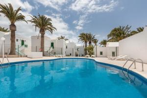 une grande piscine avec des palmiers en arrière-plan dans l'établissement Santa Úrsula 21, à Costa Calma