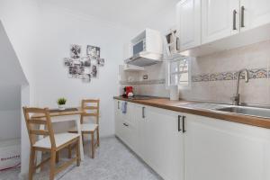 - une cuisine avec des placards blancs, un évier et une table dans l'établissement Santa Úrsula 21, à Costa Calma