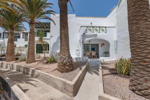 un bâtiment blanc avec des palmiers devant dans l'établissement Santa Úrsula 21, à Costa Calma