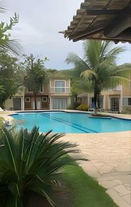 uma grande piscina com palmeiras e um edifício em Agradável Casa em Cond de frente para a Praia Rasa em Armacao dos Buzios