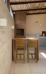 uma cozinha com uma mesa de madeira e 2 cadeiras em Agradável Casa em Cond de frente para a Praia Rasa em Armacao dos Buzios