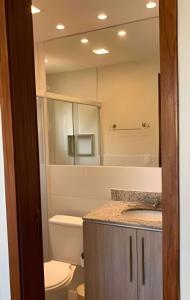 um banheiro com um vaso sanitário, uma pia e um espelho em Agradável Casa em Cond de frente para a Praia Rasa em Armacao dos Buzios