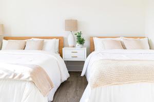 two beds with white sheets and a night stand with a lamp at Modern 5-bedroom House FREE parking in Los Angeles