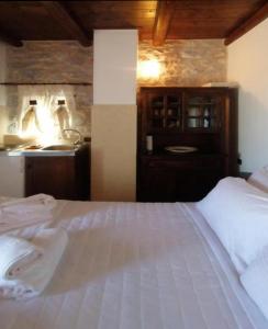 a bedroom with a white bed and a sink at Mani Fort Charabos in Ayía Kiriakí