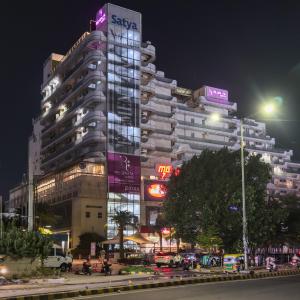 グルガオンにあるLeModCasa Pearl house, Smart luxurious comfortの夜の街にあるネオンサインのある高層ビル