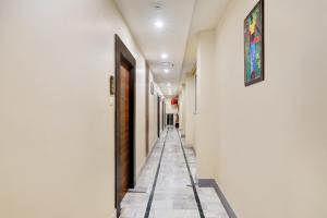a hallway with white walls and a tile floor at Super Townhouse Kankarbagh Formerly Kunwar Alcajars in Patna