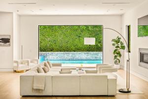 ロサンゼルスにあるLuxurious Retreat - Modern House with Poolの白いソファと大きな窓のあるリビングルーム