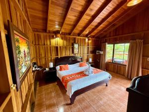 a bedroom with a bed in a room with wooden walls at Hotel La Pradera del Arenal in Fortuna