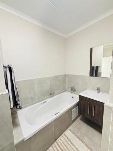 a white bathroom with a tub and a sink at Right at home in Boksburg +26 photos