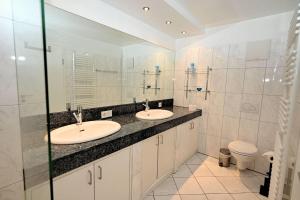 a bathroom with two sinks and a toilet at Skandinavienblick-1-5-Strandstern in Hohwacht +18 photos