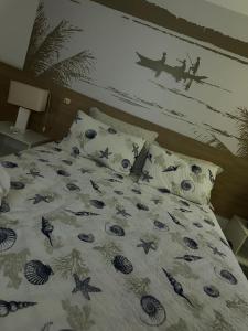 a bed with a comforter and pillows with a painting on the wall at Iloa Flat resort Apt 202 bloco i in Barra de São Miguel +18 photos