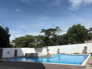 a large swimming pool with a white wall at Lindo Apartaestudio in Ricaurte +5 photos
