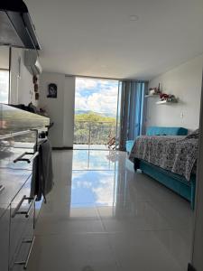 a room with a bed and a kitchen with a large window at Lindo Apartaestudio in Ricaurte