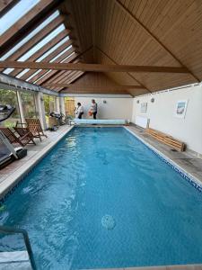 a large swimming pool with two people standing in it at Thatchers Barn in Diss